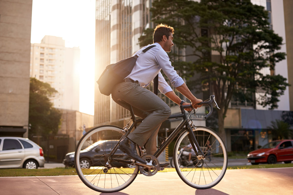 Büroangestellter fährt mit dem Firmenfahrrad auf einer belebten Straße